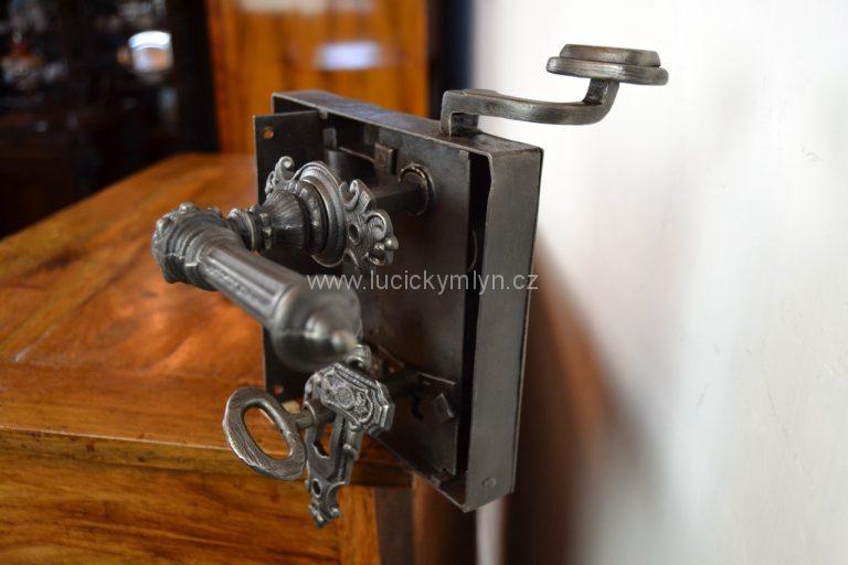Větší dveřní zámek krabicového typu, se zdobenými štítky, klikami a funkčním klíčem