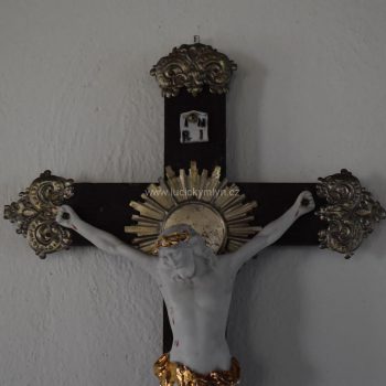 Starožitný kříž, přizdobený aplikacemi z tlačeného plechu a osazený Kristem z bílého biskvitu