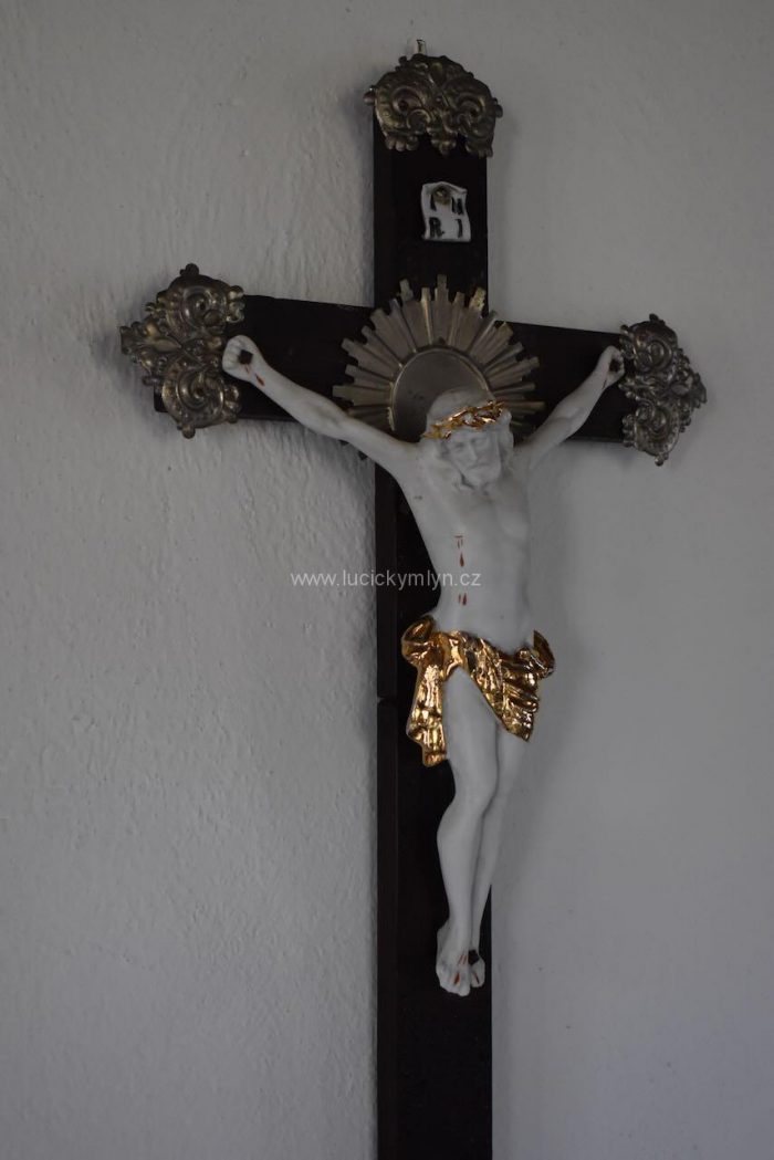Starožitný kříž, přizdobený aplikacemi z tlačeného plechu a osazený Kristem z bílého biskvitu