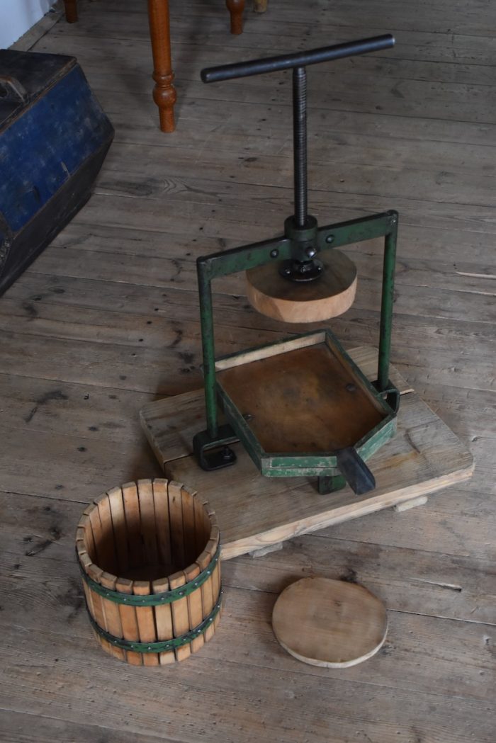 Historický ruční lis na ovoce a révu s pevnou ocelovou konstrukcí, jež je k dřevěné podstavě připevněna šrouby