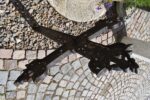 Dekorativní starožitný litinový kříž s důmyslně proplétaným květinovým motivem a nápisem INRI, vše zasazeno do jemně prořezávané stylizace v masivní, ale vzdušné rámové konstrukci daného tvaru