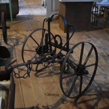 Starožitná zemědělská upínací náprava s koly z oracího zařízení.