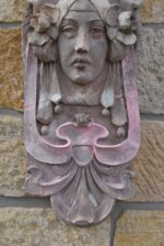 Secesní fasádní štukatérský reliéf s hlavou ženy a florálně ornamentálním dekorem.