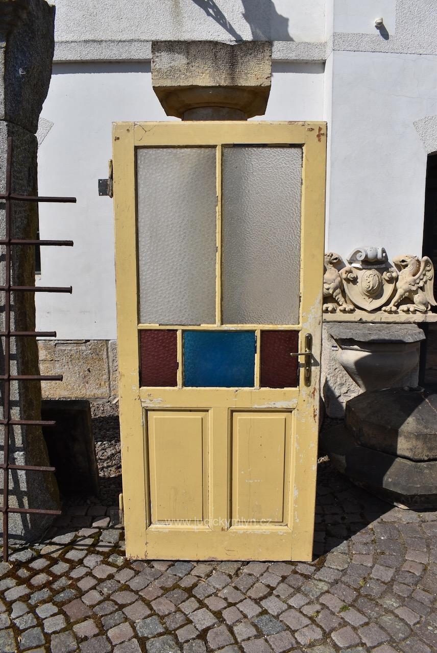 Starožitné rámové dveře z období vrcholné secese osazené spodními profilovanými kazetami a prosklenou vrchní částí, níže souměrně rozčleněnou dvojitým dělením - počátek 20. století, 198 cm x 87,7 cm (Kopírovat) Starožitné rámové dveře se secesními kazetami a barevnými prosklenými poli z počátku 20. století.