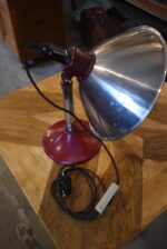 Prvorepubliková industriální stolní lampa s hliníkovým stínidlem a bakelitovou zástrčkou.