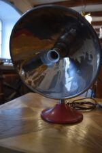 Prvorepubliková industriální stolní lampa s hliníkovým stínidlem a bakelitovou zástrčkou.