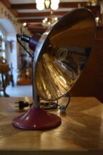 Prvorepubliková industriální stolní lampa s hliníkovým stínidlem a bakelitovou zástrčkou.