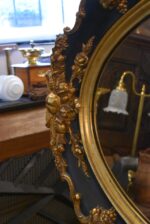 Starožitné oválné nástěnné zrcadlo v černo-zlatém rokokově historizujícím rámu