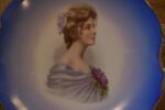 Pár starožitných secesních porcelánových talířů s portréty dam a zlatými uchy.