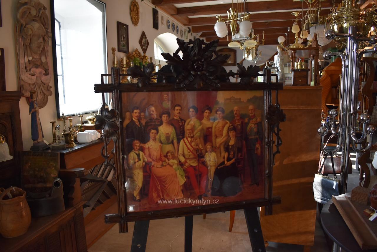 Středně větší starožitný bohatě řezaný rám vkusně okrášlený květinovými motivy i symboly hojnosti z lipového tmavě mořeného dřeva osazený zánovní kopií historického kolorovaného tisku Starožitný řezaný rám z lipového dřeva s kolorovaným tiskem habsburské panovnické rodiny s Františkem Josefem I.