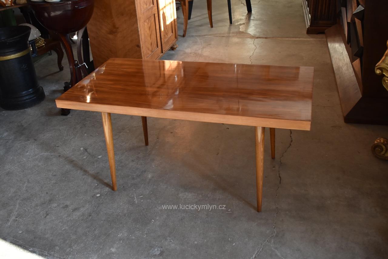 Nižší a stabilní historický konferenční retro stolek s užší a silnější ořechem dýhovanou deskou osazený šikovně šroubovacíma kónickýma nohama z hladce soustruženého a mořeného buku Historický retro konferenční stolek s ořechovou dýhovanou deskou a soustruženými nohami.