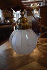 Starožitná párová závěsná světla z mosazi s geometrickými matovými skleněnými koulemi.