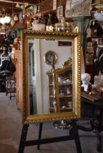 Starožitné nástěnné zrcadlo v zlatém biedermeirovském rámu s listovcem a vejcovcem.