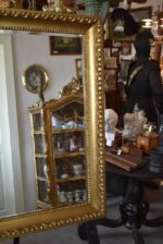 Starožitné nástěnné zrcadlo v zlatém biedermeirovském rámu s listovcem a vejcovcem.