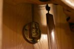 Starožitné prvorepublikové nástěnné kyvadlové hodiny v kubizující skříňce z kontrastních dřev