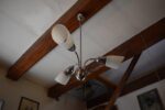 Elegantní retro tří-ramenný lustr s chromovaným povrchem a mléčně bílými válcovými stínidly.