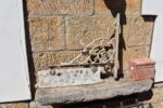 Oboustranná litinová vývěsní cedule v historizujícím stylu na vinuté konzoli.