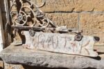Oboustranná litinová vývěsní cedule v historizujícím stylu na vinuté konzoli.