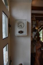 Starožitné prvorepublikové nástěnné kuchyňské hodiny s bílým porcelánovým čílkem a kyvadlem.