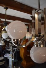 Starožitný funkcionalistický tří-ramenný chromovaný lustr s mléčně narůžovělými skleněnými koulemi.
