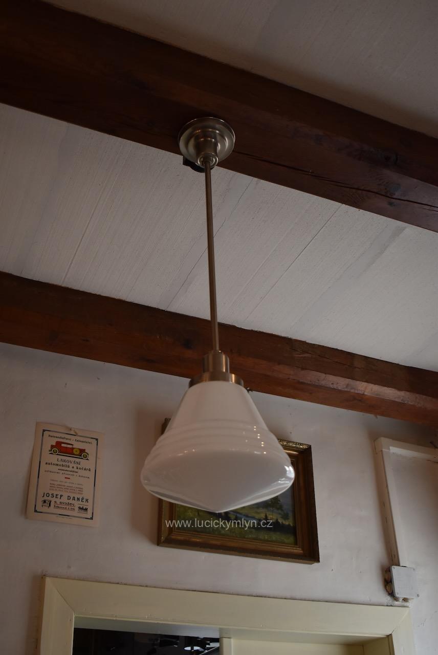 Delší starožitné modernistické designové závěsné světlo či lustřík navržený v lehce kubizujícím stylu ART-DECO z chromované mosazi osazené větším mírně hrotitým a nápadně kónickým stínidlem z opálového skla oživeným vrstvenou prstencovou profilací u spodního okraje Starožitný lustr ART-DECO z chromované mosazi s kónickým opálovým stínidlem.