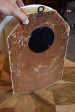 Starožitné kuchyňské hodiny s oválným porcelánovým ciferníkem a rokokovými stínovými postavičkami.