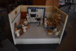 Starožitné diorama historické pekárny s kachlovou pecí a figurkami pekařů.