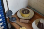 Starožitné diorama historické pekárny s kachlovou pecí a figurkami pekařů.