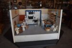 Starožitné diorama historické pekárny s kachlovou pecí a figurkami pekařů.