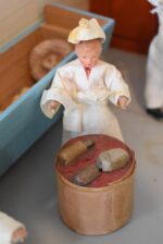 Starožitné diorama historické pekárny s kachlovou pecí a figurkami pekařů.