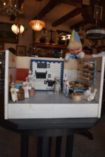 Starožitné diorama historické pekárny s kachlovou pecí a figurkami pekařů.