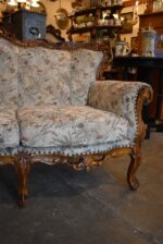Historyczna sofa z drewna orzechowego w stylu rokokowym, z tapicerką z motywem kwiatów łąkowych.