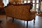 Historyczna sofa z drewna orzechowego w stylu rokokowym, z tapicerką z motywem kwiatów łąkowych.