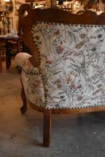 Historyczna sofa z drewna orzechowego w stylu rokokowym, z tapicerką z motywem kwiatów łąkowych.
