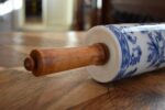 Starožitný porcelánový váleček s cibulákovým motivem a bukovými dřevěnými držadly.