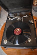 Starožitný kufříkový gramofon Wellington Gramophones s deskou His Master's Voice.