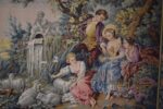 Starožitná žakárová tapiserie Aubusson s pastýřskou scénou a květinovou bordurou.