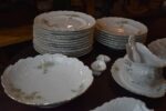 Starožitný jídelní porcelánový servis PULS Ostrov s květinovým dekorem a zlacenými okraji.