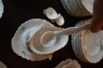 Starožitný jídelní porcelánový servis PULS Ostrov s květinovým dekorem a zlacenými okraji.