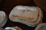 Starožitný jídelní porcelánový servis PULS Ostrov s květinovým dekorem a zlacenými okraji.