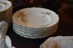 Starožitný jídelní porcelánový servis PULS Ostrov s květinovým dekorem a zlacenými okraji.