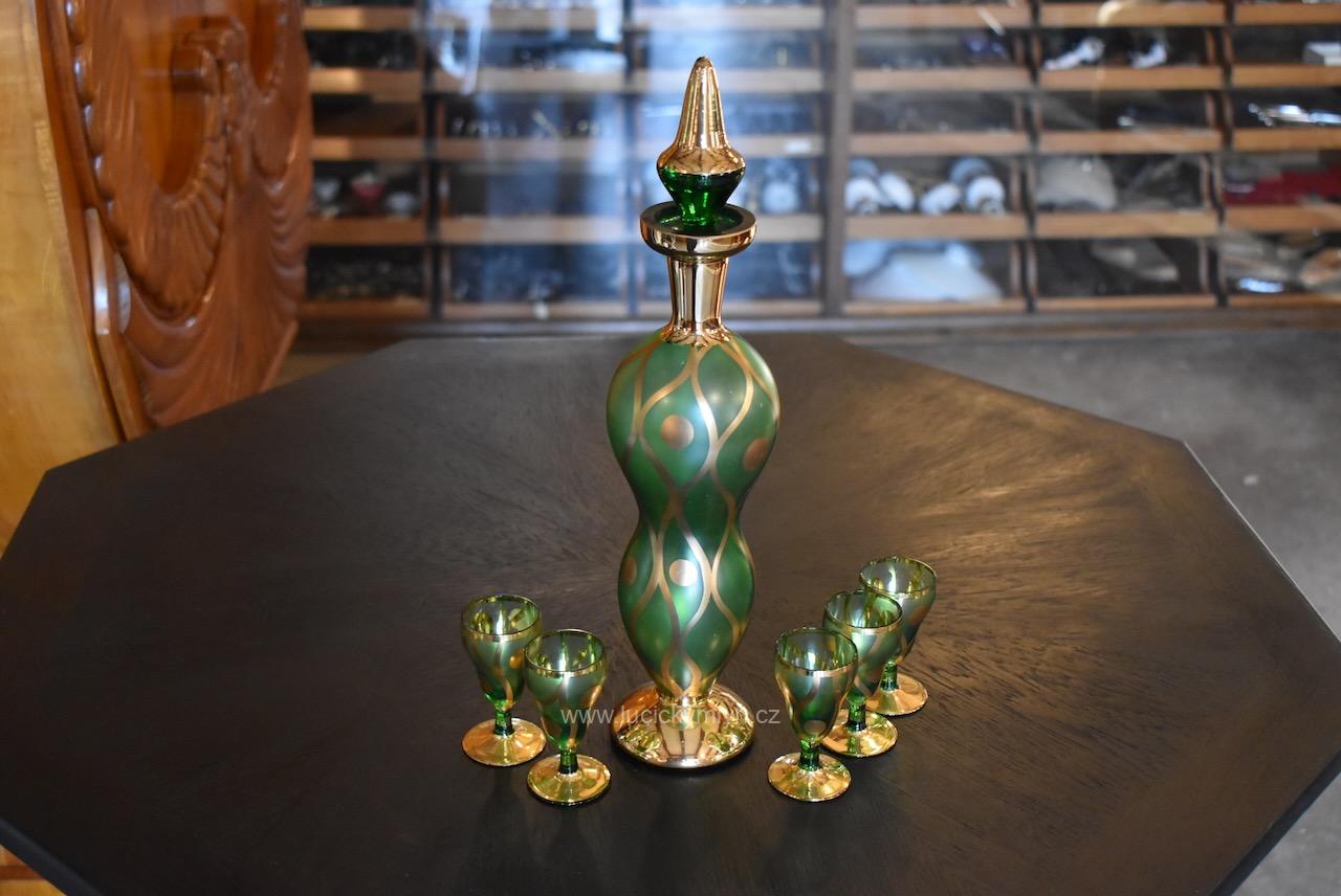 Nadčasově ztvárněná a bohatě zlacená retro likérová souprava z českého skla Bohemia Glass skládající se z vysoké karafy se soustruž. tělem osazeným zátkou a pěti skleničkami též na nožce s širokým terčíkem (Kopírovat) Retro likérová souprava Bohemia Glass ze zeleného skla se zlaceným dekorem.