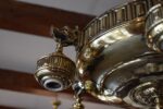 Starožitný secesně klasicizující mosazný lustr s rameny ve tvaru vlčích hlav.