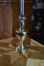 Starožitná mosazná petrolejová lampa ve tvaru poháru se skleněným cylindrem z okolo roku 1910.