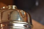 Starožitná mosazná petrolejová lampa ve tvaru poháru se skleněným cylindrem z okolo roku 1910.