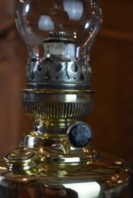 Starožitná mosazná petrolejová lampa ve tvaru poháru se skleněným cylindrem z okolo roku 1910.