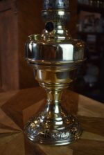 Starožitná mosazná petrolejová lampa ve tvaru poháru se skleněným cylindrem z okolo roku 1910.