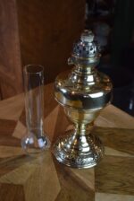 Starožitná mosazná petrolejová lampa ve tvaru poháru se skleněným cylindrem z okolo roku 1910.
