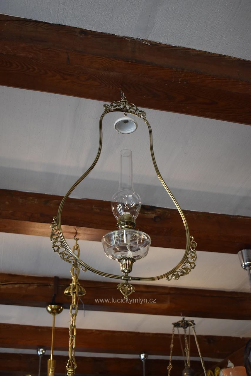 Nevšední starožitná petrolejová lampa se závěsným trubicovým rámem ve tvaru hrušky ztvárněná v secesně historizujícím stylu okolo r. 1900 z lité i tlačené mosazi a skla Starožitná secesní petrolejová lampa s prořezávaným mosazným rámem z okolo roku 1900.