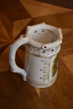 Starožitný žertovný porcelánový půllitr s výjevem z Prodané nevěsty a prolamovaným okrajem.